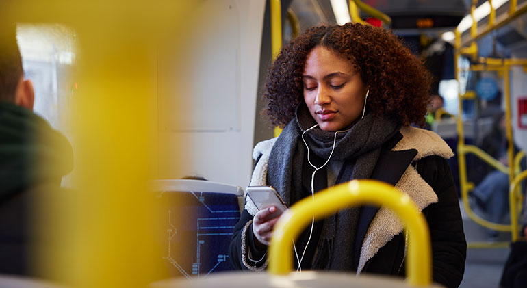 En tjej sitter på en buss och kolla på mobilen.
