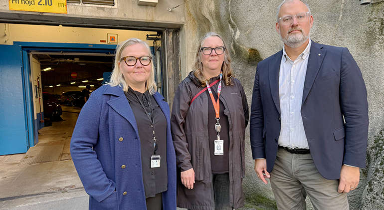 Två kvinnor och en man framför garageöppning