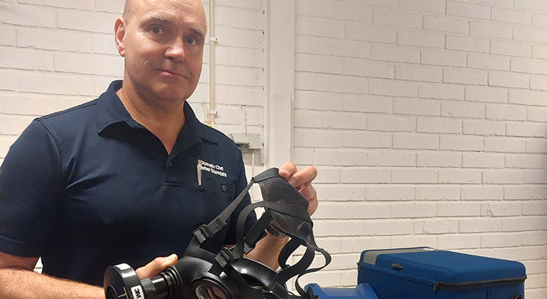 Man med andningsmask i händerna